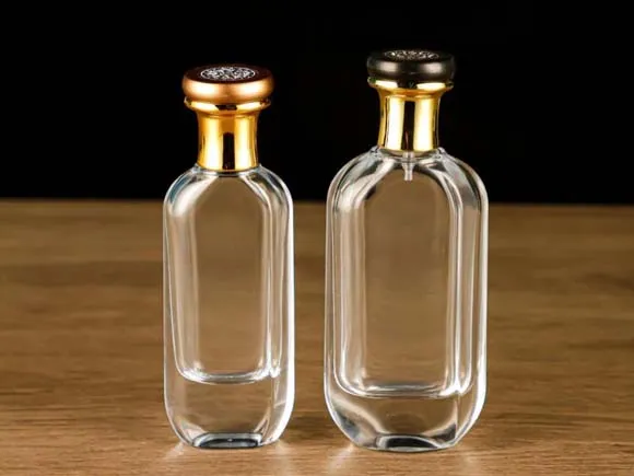 Two clear rectangular fragrance bottles with rounded shoulders and gold-colored caps