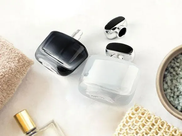 Dark and clear rounded-square perfume bottles with detached caps